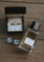 Gold ring in black box, Banana Republic 06 perfume, penguin cufflinks on wood surface. Elegant, rustic vibe.