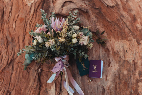 bridal bouquet, vow booksx, and rings on red rocks in Arches National Park, Utah