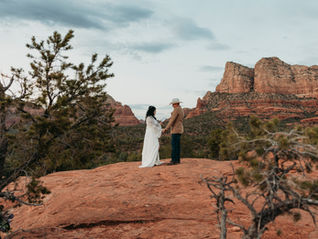 Bride and groom holding hands during their elopement in Sedona with red rocks behind them.