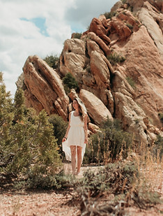Woman in a white dress walking in front of a rock formation in Colorado