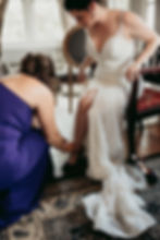 maid of honor putting shoes on a bride