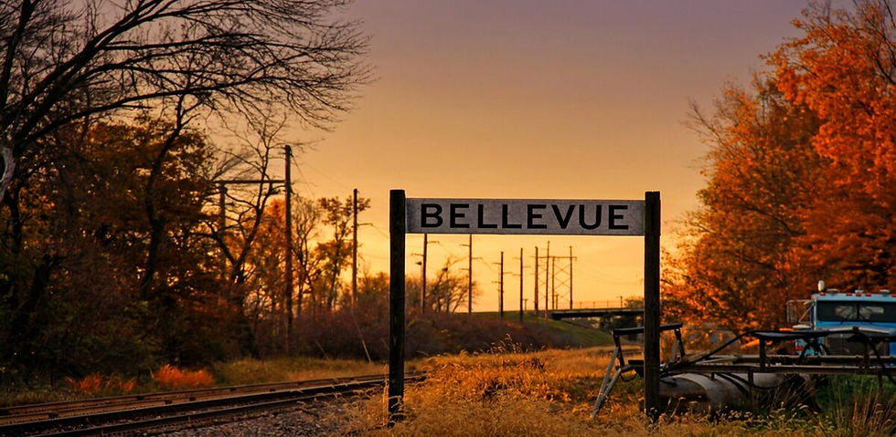 Bellevue sign by railroad tracks at sunset
