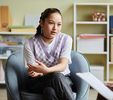 A-young-woman-seated-in-a-chair-engages-in-conversation-with-another-woman-nearby-1024x682