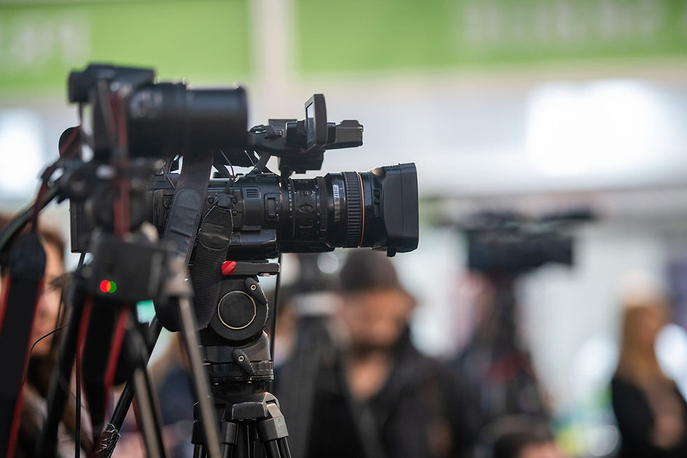 Professional video production cameras on tripods at an event.