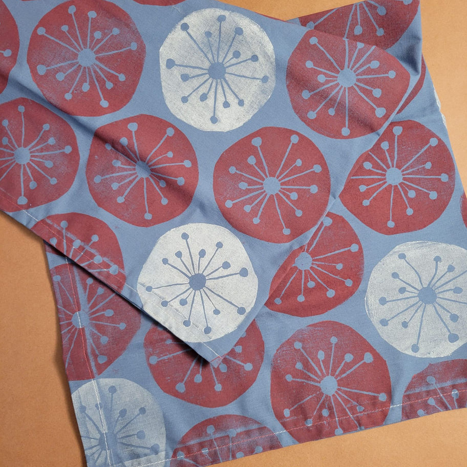Detail shot of a blue cotton bandanna featuring hand-printed red and white mid-century atomic starburst circles