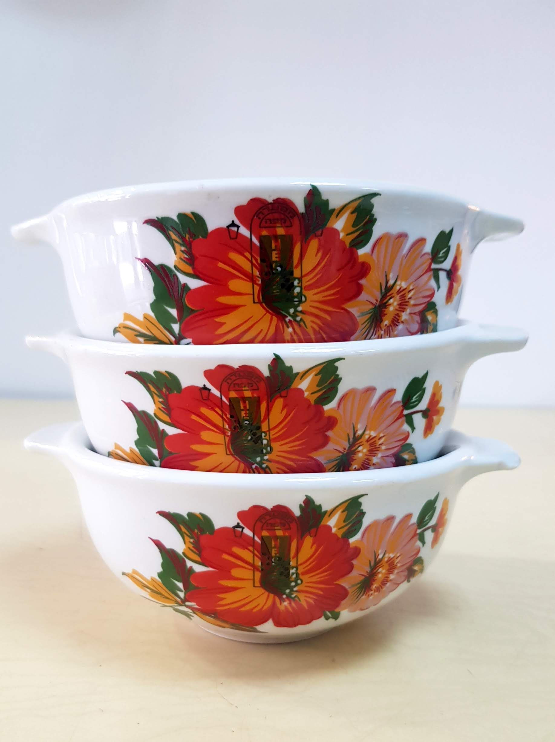 זוג צלוחיות בהירות עם פרחים בכתום אדום ולוגו מסעדה עליהם - נעמן