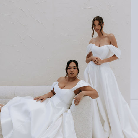 Two models in Eden Wedding Dress, sitting and standing next to the sofa by Kelly Lin Couture at Bridal Boutique, Bury, Manchester