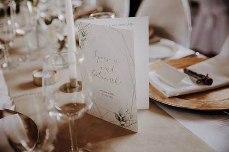 Ein dekorierter Hochzeitstisch auf den Waldofer Höfen in Ochtendung mit einem Speisemenü in der mitte