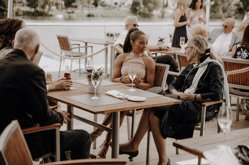 Gäste unterhalten sich auf Veranda und sitzen an Tisch