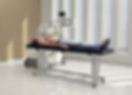 Patient liegt auf Liege und hat Stoßwellentherapiegerät neben sich stehen