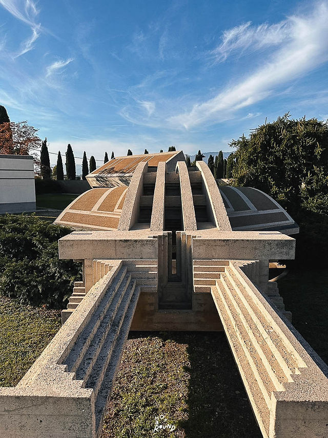 Brion Tomb หรือ Brion Cemetery ผลงานชิ้นเอกของ Carlo Scarpa ใกล้เมือง Treviso ประเทศอิตาลี คือสถานที่ที่ทำให้คำว่า "สุสาน" มีความหมายมากกว่าพื้นที่แห่งการจากลา ผ่านสถาปัตยกรรม แสง น้ำ สวน และรายละเอียดอันประณีตที่หลอมรวมเป็นบทกวีแห่งชีวิต ความรัก และความตาย พาไปรู้จักหนึ่งในจุดหมายที่คนรักสถาปัตยกรรมทั่วโลกใฝ่ฝันจะมาเยือนสักครั้ง พร้อมข้อมูลการเดินทางและคำแนะนำสำหรับการวางแผนทริปในอิตาลี วิธีการเดินทางไปยัง Brion Tomb รีวิว Brion Tomb วิธีการเดินทาง Tomba Brion เที่ยวอิตาลี Italy architecture เที่ยวเมือง Treviso Road Trip Italy ขับรถเที่ยวอิตาลี