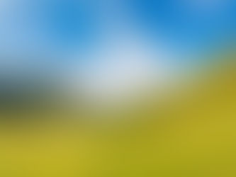 Scenic landscape of green hills and a lake under a vibrant blue sky with wispy clouds. Peaceful and bright atmosphere.