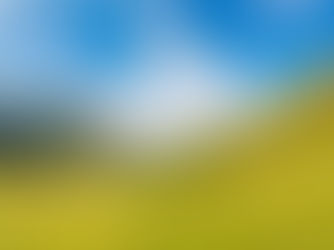 Green hills and a serene lake under a bright blue sky with wispy clouds. The scene is tranquil and open, evoking a peaceful mood.