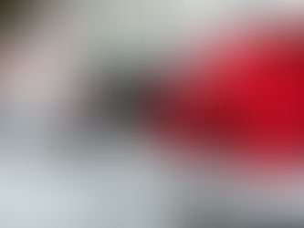 Car salesman dressed as Santa standing next to a new car with a large red bow during a holiday car sales event.