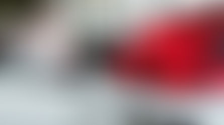 Car salesman dressed as Santa standing next to a new car with a large red bow during a holiday car sales event.