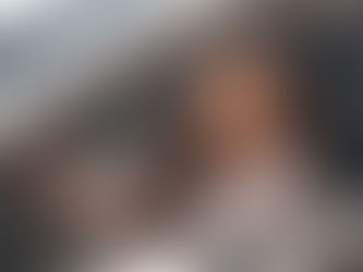 Woman sitting in the driver’s seat of a car, looking ahead through the open window in daylight