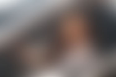 Woman sitting in the driver’s seat of a car, looking ahead through the open window in daylight