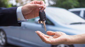 A man handing a woman the keys to a rental car.