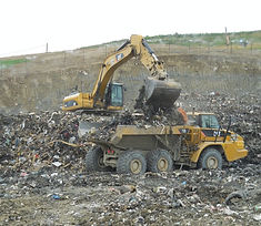 An excavator loading an offroad truck with garbage