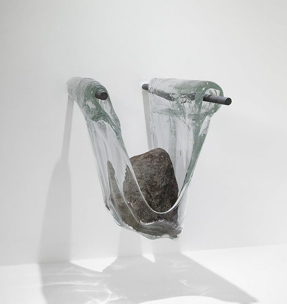 Curator Jocelyne Prince has brought together five artists: Justin Ginsberg, Romina Gonzales, Ashley Raye Harris, Matthew Day Perez, and Alexander Wenstrup, who have an acute understanding of how just a few millimeters of glass can shift our perception of the world. Each work in this exhibition catalyzes the optical and sculptural space that exists within a sheet of glass. In some cases, the surface of the glass has been disrupted, or bears the marks of the action of its making, or the glass composition has been specially concocted to refract light, or the tiniest amount of air is trapped and visually manifested. A fascination with surface, the space just beyond the surface, what we see through the glass, the space within the glass, and what we see reflected in the glass preoccupies these artists.
The works in this exhibition have been selected in conjunction with, and as a complement to the research and activities that are part of the November 2026 WheatonArts symposium on window glass production methods, “Transparent Thresholds.”
