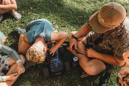 kids and dads working on remote control cars while camping