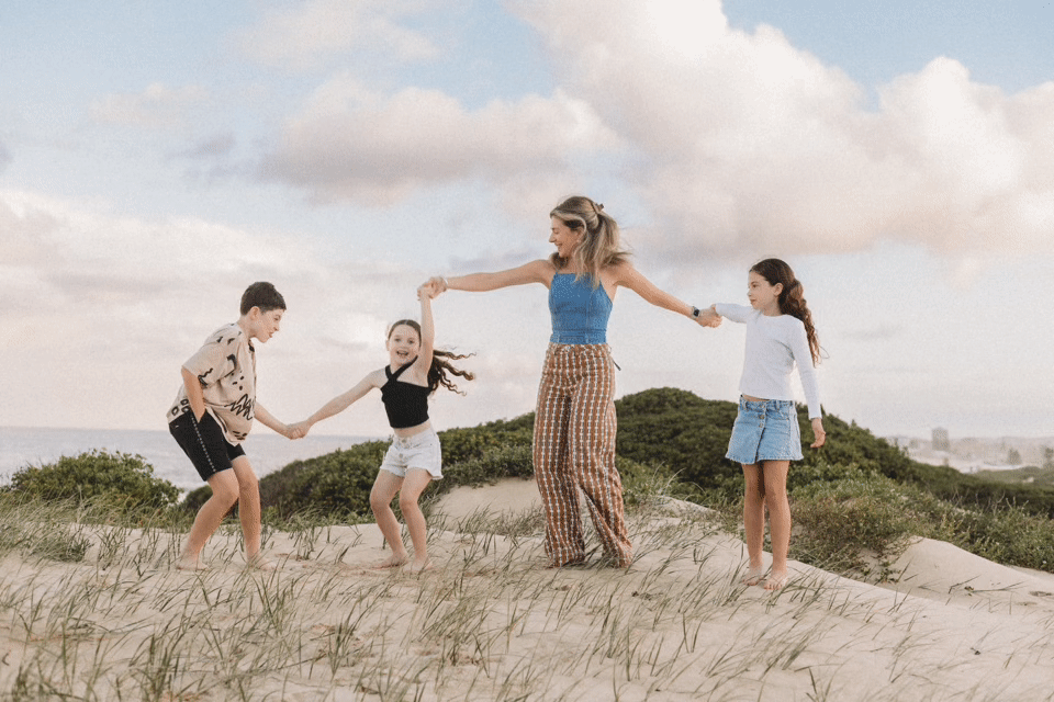 mum and kids dancing on the beach as the sun sets in the entrance nsw