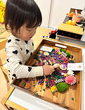 Child exploring a sensory learning kit with hands-on materials, supporting fine motor and early literacy development.
