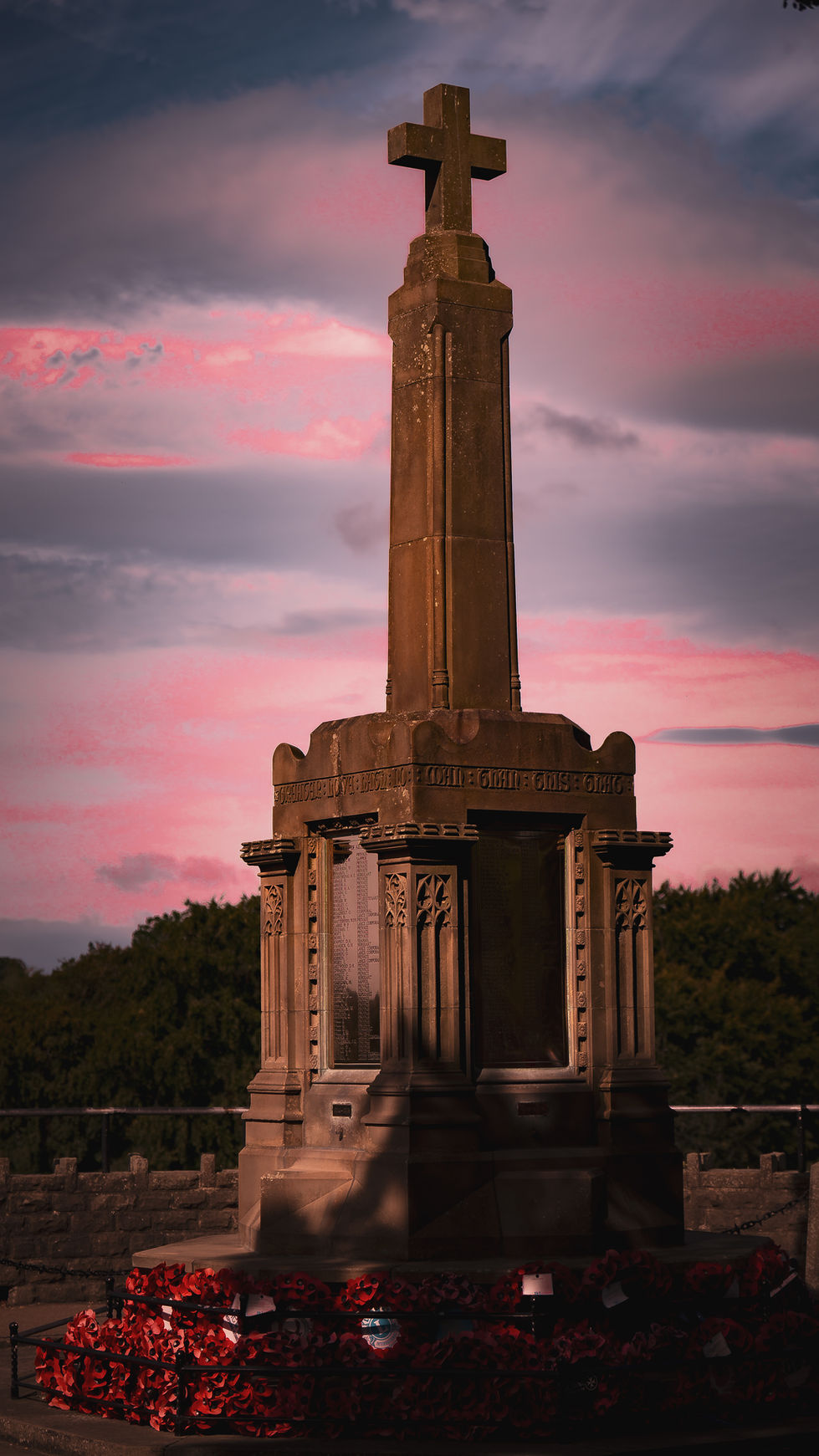 Stone war memorial cross at sunset