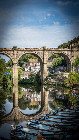 Stone viaduct reflected in calm water with boats