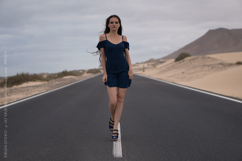 Runway model is catwalking in the middle of street.