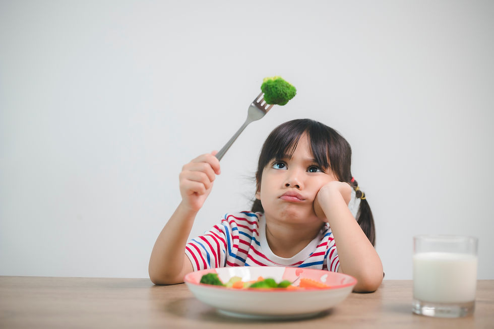 A child staring at broccoli, not eating it.