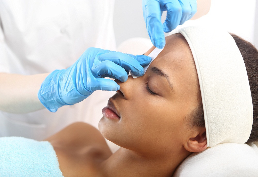 Esthetician performing eyebrow wax
