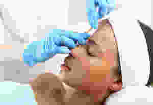 Esthetician performing eyebrow wax