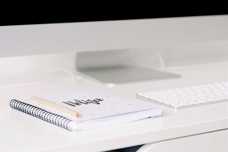 Ein Notizbuch und eine Tastatur vor einem Computer-Bildschirm.