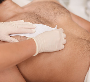 Cosmetologist doing waxing on torso of unrecognizable male client.jpg