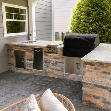 Stone outdoor kitchen with sink, side burner, and built-in grill on paver patio in Charlotte NC