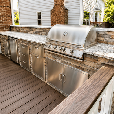 Outdoor kitchen on composite deck with stacked stone base, granite counter, built-in grill, and fridge in Charlotte NC