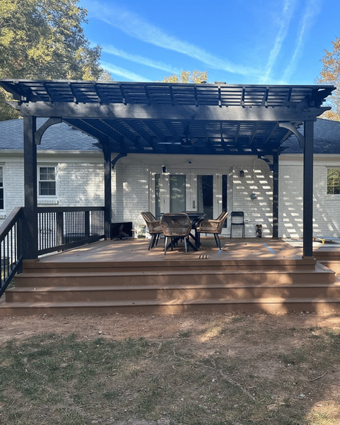 Completed backyard deck with sleek black pergola and dining space, designed for modern outdoor living in Charlotte.
