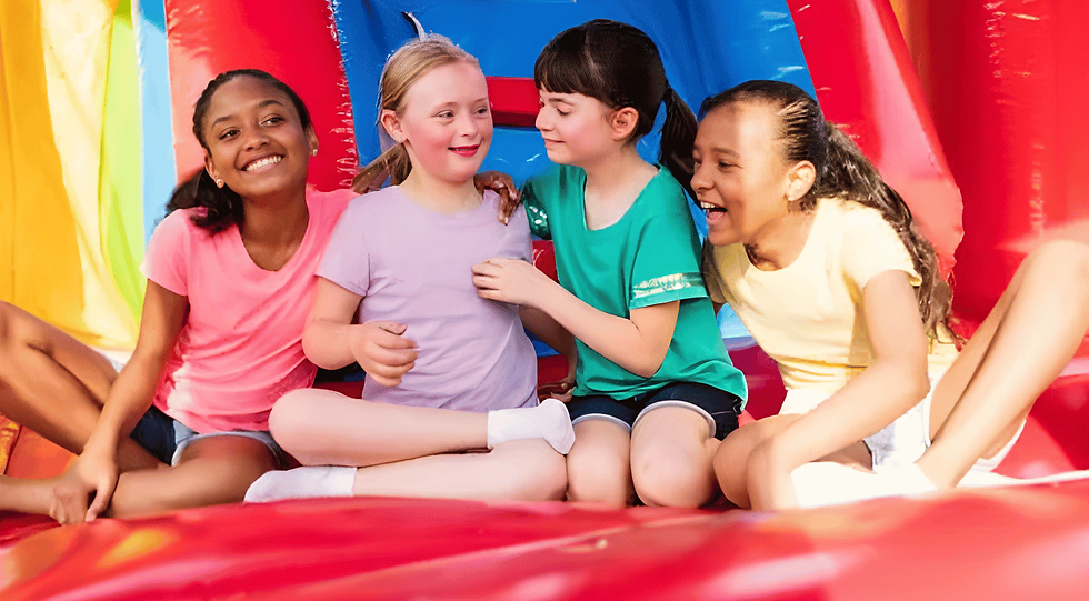 Girls laughing and playing together inside a colorful bounce house at a birthday party