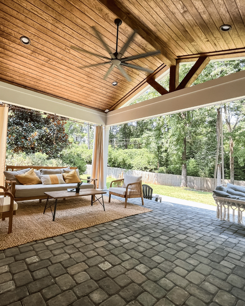 Beautiful covered patio in Charlotte featuring wood ceiling, ceiling fan, cozy seating, and outdoor swing—perfect for relaxing or entertaining.