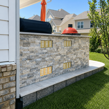 Stone outdoor kitchen island with vented panels, kamado grill, and travertine patio in Charlotte NC