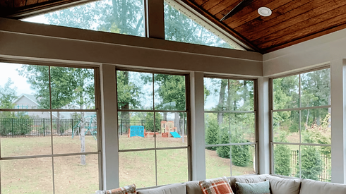 Interior view of screened porch with large windows, vaulted ceiling, and cozy seating overlooking backyard in Charlotte