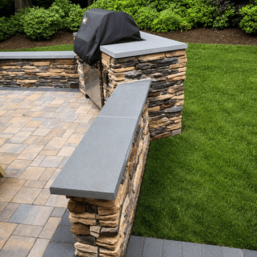 Built-in Weber grill in stacked stone island with seating walls on paver patio in Charlotte NC