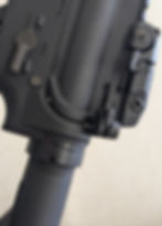 Close-up of a black rifle’s safety selector, showing "SAFE" and "FIRE" settings. Background is a neutral, light color.