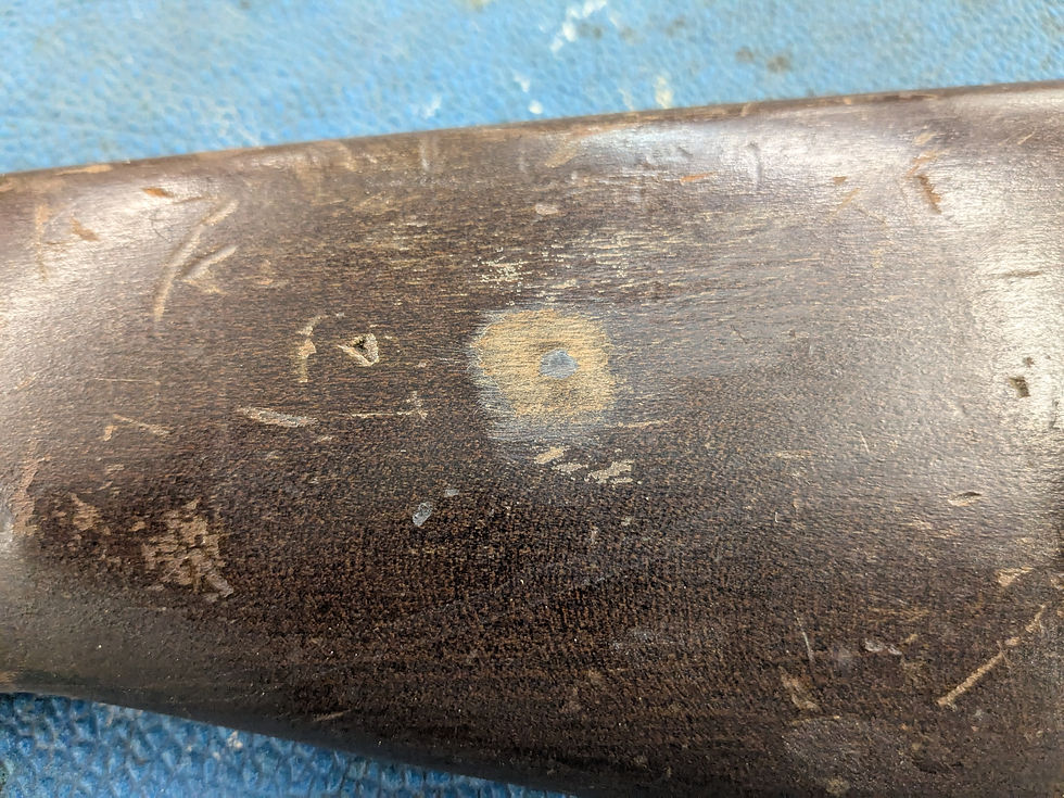 Close-up of a wooden surface with scratches and a faded circular mark. The background is a textured blue fabric, creating a rustic look.