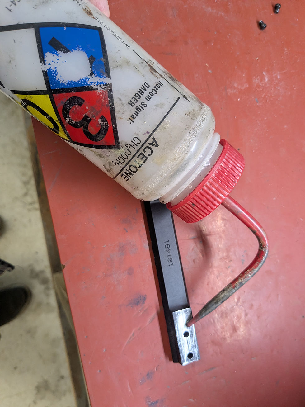 Bottle of acetone lying across the scope base during degreasing on a red bench top