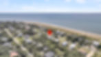 Aerial view of beachfront town, house marked by red pin