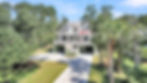 Elevated house with balconies, long driveway, and trees