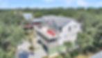 Multi-story house with red chairs on upper balcony, surrounded by trees