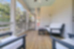 Screened porch with wooden floor, chairs, and sofa